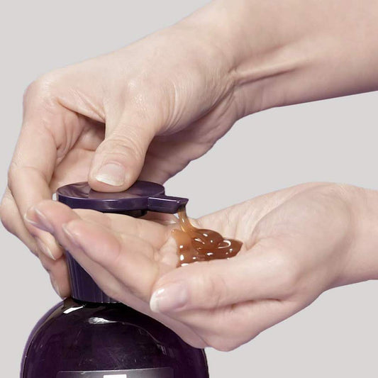 Person opening a purple bottle and squeezing out a brown gel-like substance.